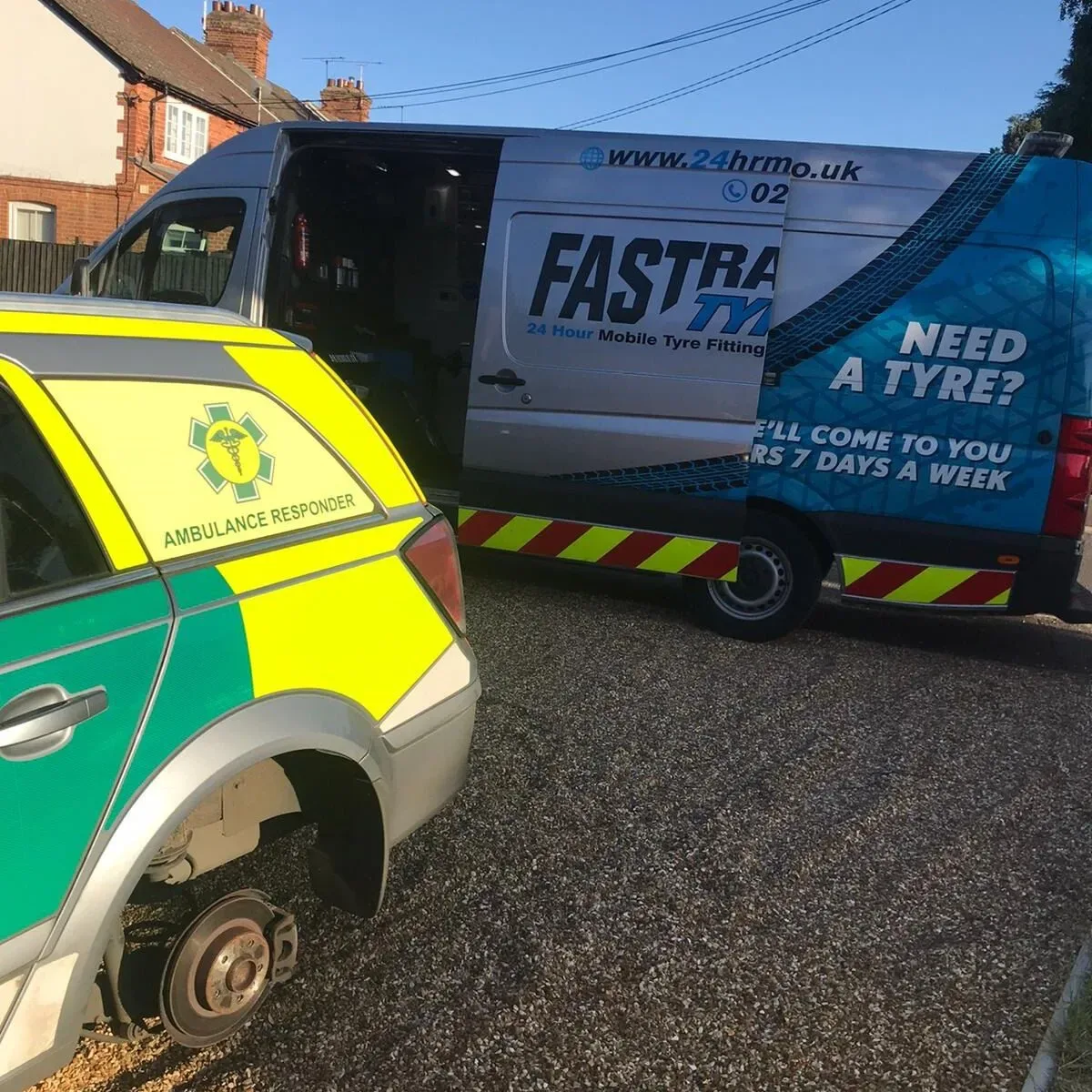 Fastrack Tyres van beside an ambulance responder car with its wheel removed during a daytime roadside tyre change
