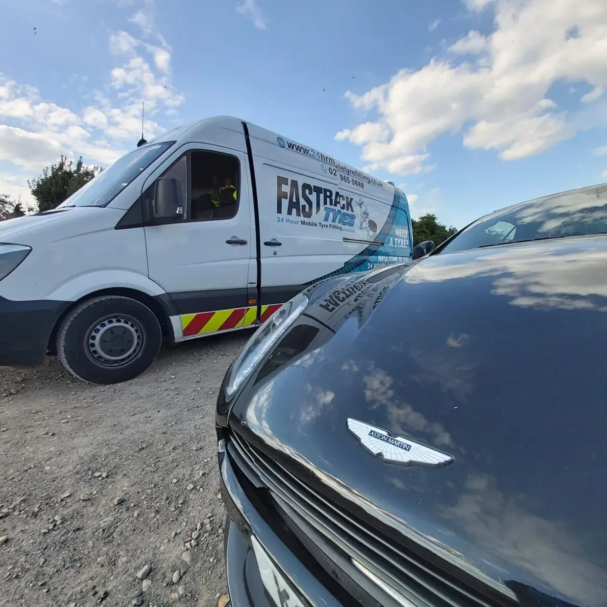 Aston Martin DB11 bonnet badge with the Fastrack Tyres van reflected in the paintwork