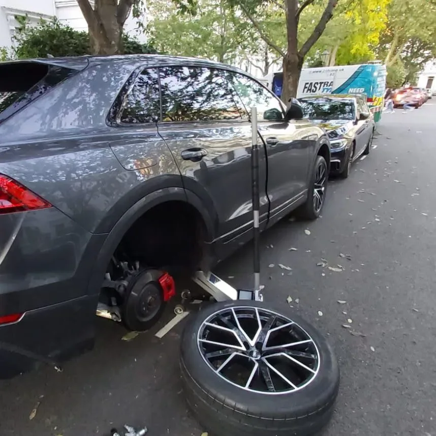 Grey Audi Q8 with its wheel removed and the diamond-cut alloy resting on the road during a Belgravia tyre change