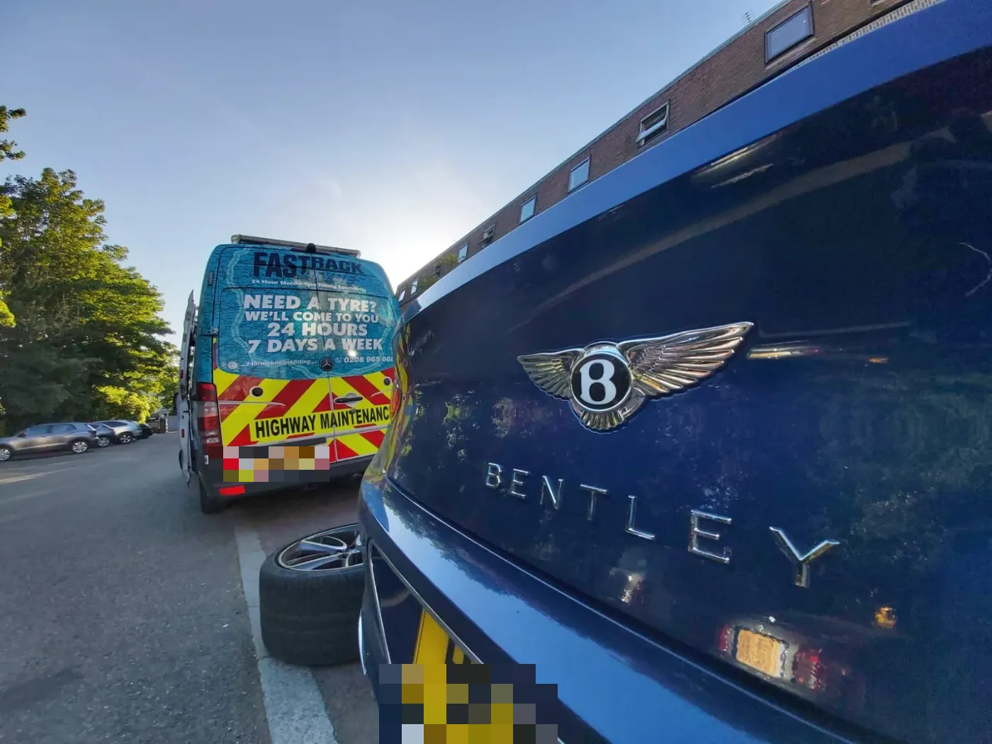 Blue Bentley Continental GT rear badge detail during a wheel change with the Fastrack Tyres van behind