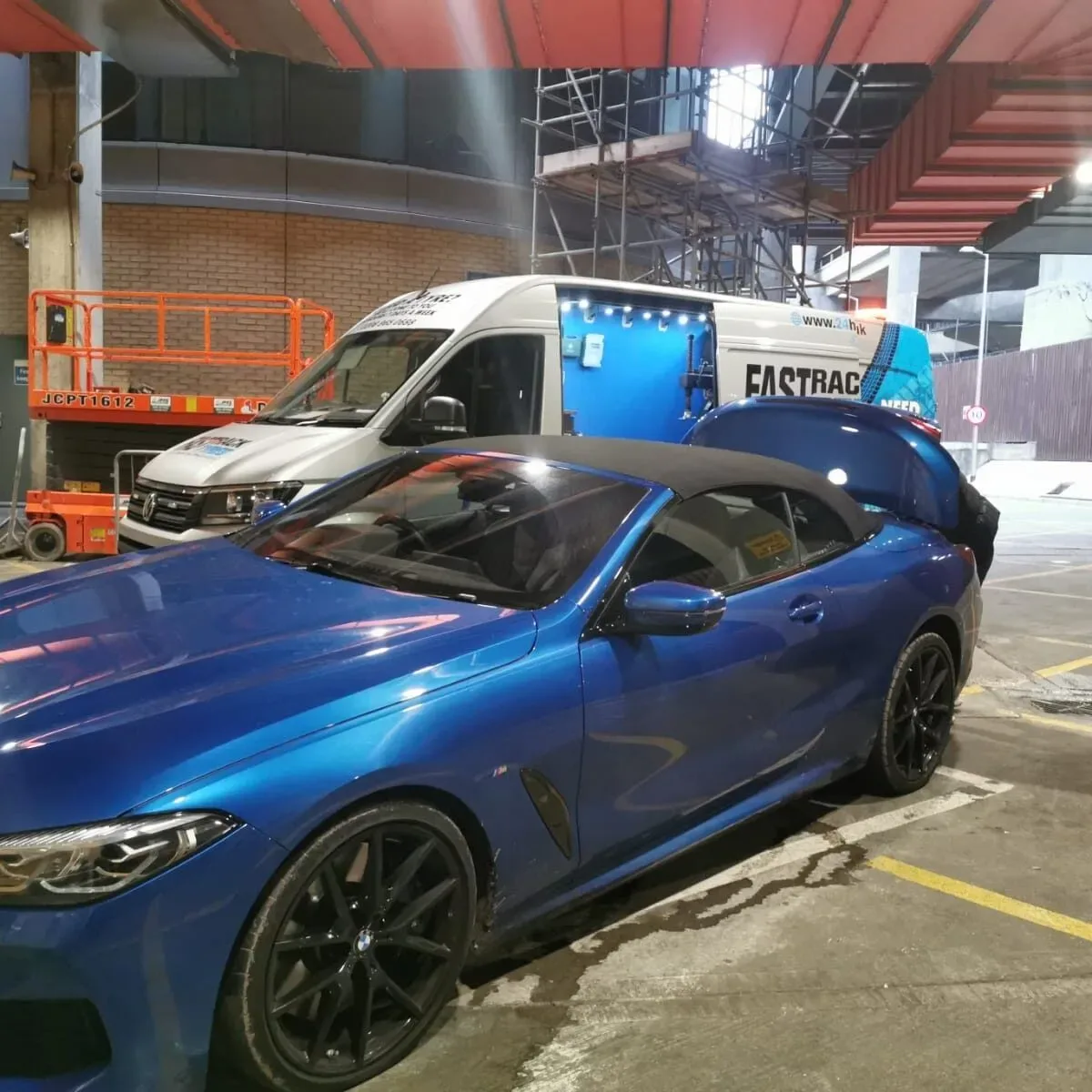 Blue BMW 8 Series convertible parked under cover at night with the Fastrack Tyres van behind