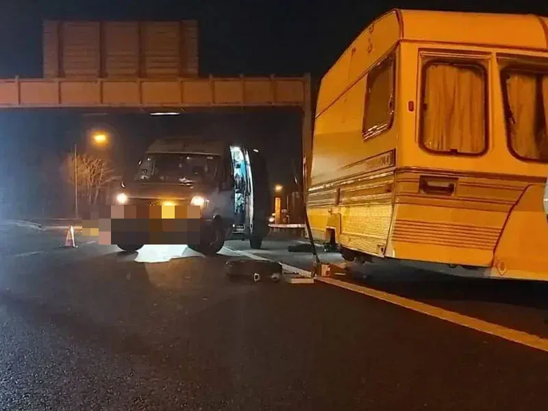 Fastrack changing a tyre on a touring caravan at night under a motorway bridge, van attending with cones out