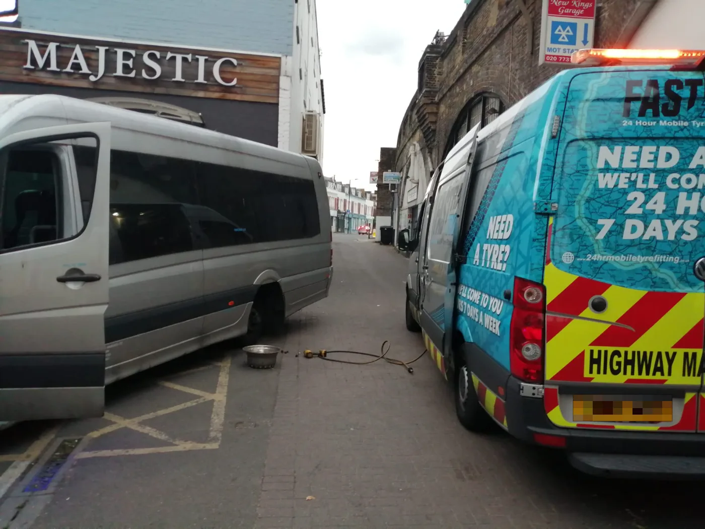 Fastrack Tyres branded van on a roadside tyre call-out beside a silver minibus on a London side street
