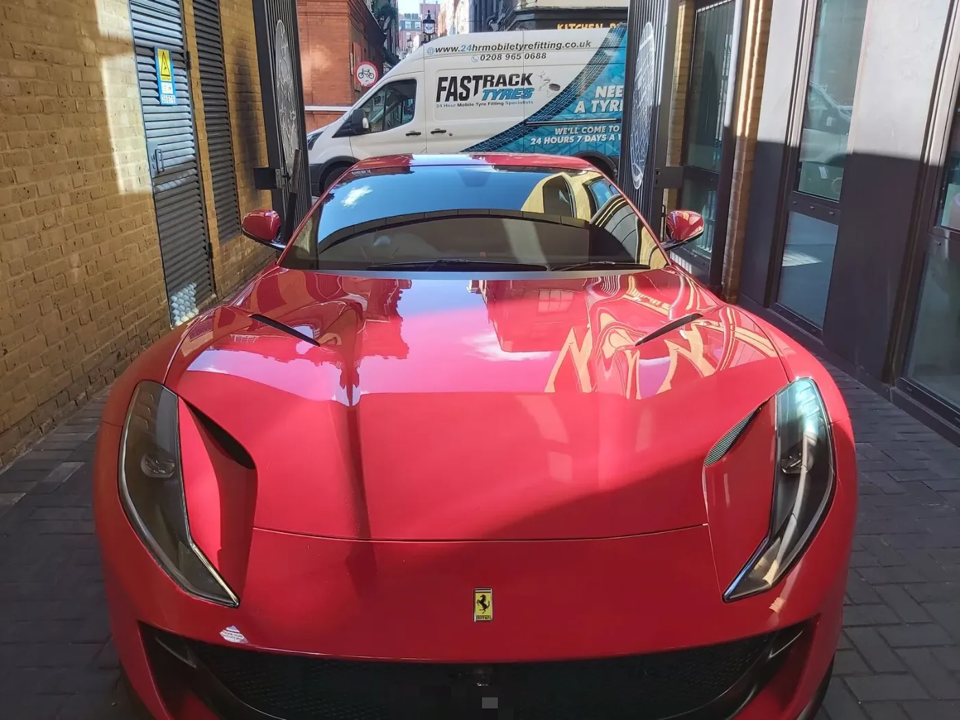 Red Ferrari 812 Superfast in a narrow London mews with the Fastrack Tyres van behind