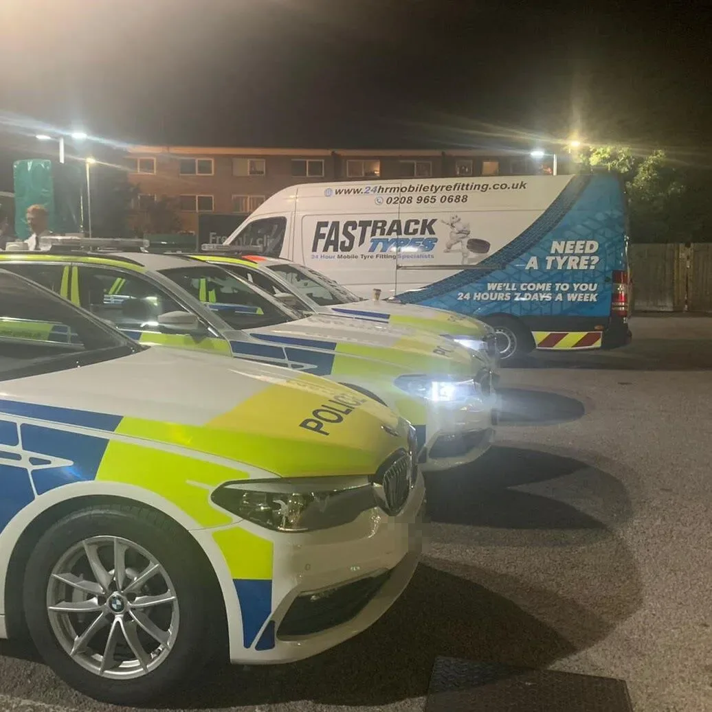 Marked police BMW 5 Series cars beside the Fastrack Tyres van during a night-time tyre call-out