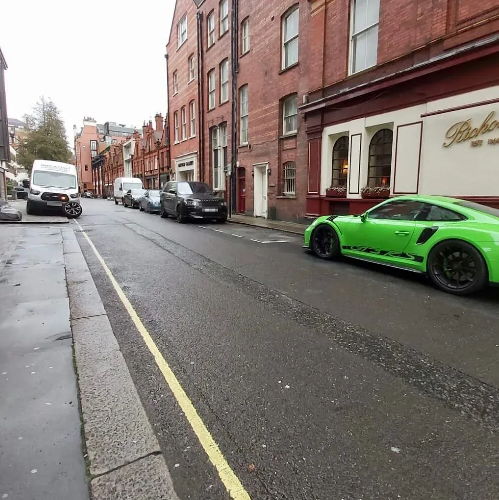Bright green Porsche 911 GT3 RS parked on a London street with the Fastrack Tyres van behind
