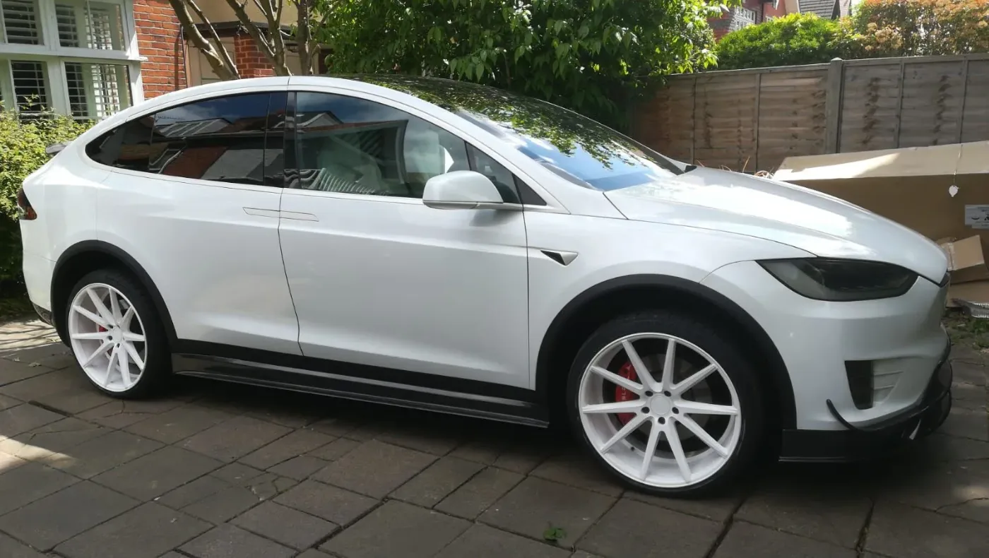 White Tesla Model X with custom white alloys parked on a residential driveway
